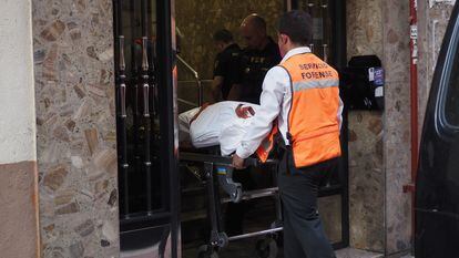 Operarios de los servicios funerarios salen de una de la dos viviendas de Valladolid donde aparecieron los cadáveres de dos mujeres y un hombre.