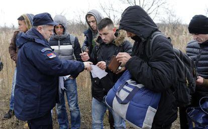 Un polic&iacute;a serbio pide la identificaci&oacute;n a varios inmigrantes kosovares en la frontera de Serbia con Hungr&iacute;a, el 6 de febrero. 