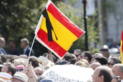 Una bandera d'Espanya amb un crespó negre durant l'homenatge a les víctimes a la plaça de Catalunya.