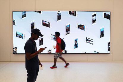 Dos hombres pasan frente a un cartel publicitario de Apple