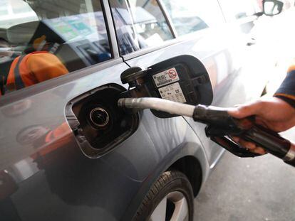 Un empleado de una gasolinera echa combustible a un coche.