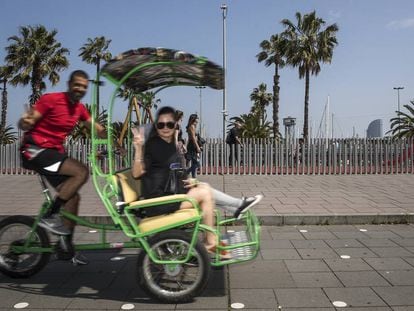 Un ‘bicitaxista‘ con una pareja de turistas en el paseo Colón de Barcelona