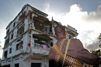 Un miliciano frente a edificio derruido en el que vive gente, agosto de 2011