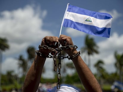 Un hombre con cadenas en las manos y una bandera de Nicaragua participa en una misa por la liberación de presos políticos.