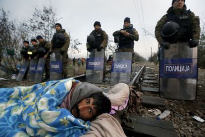Un migrante iraní en huelga de hambre se despierta frente a la policía antidisturbios, en la frontera entre Grecia y Macedonia.