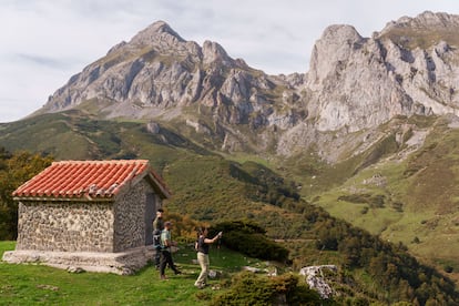Un grupo de senderistas se detiene ante un refugio de pastores en Picos de Europa, por donde transcurren rutas que parten del parador de Fuente Dé.