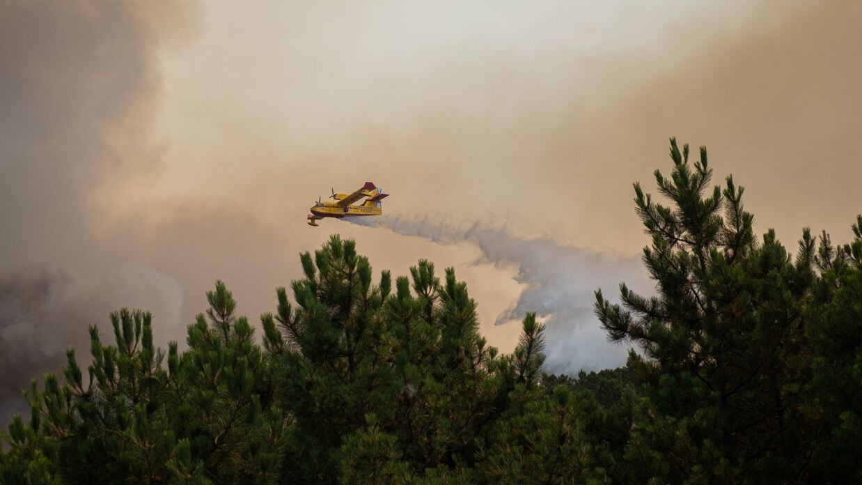 Una avioneta suelta su carga de agua sobre las llamas del incendio en Las Hurdes, que ha obligado a desalojar de sus casas a más de 300 personas.