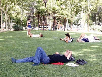 Un grupo de ciudadanos descansa en el césped de un parque en Madrid.