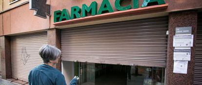 Una boticaria cierra su farmacia en la calle Guardiola i Felip para protestar por los 416 que les adeuda la Generalitat.