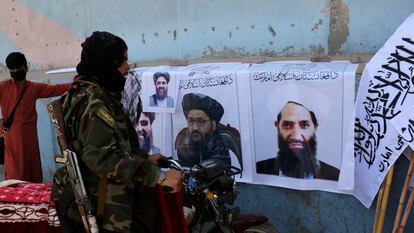 Un miliciano mira carteles de los líderes talibanes Haibatullah Akhundzada (derecha) y Abdulghani Baradar, en Kabul, el 25 de agosto de 2021.