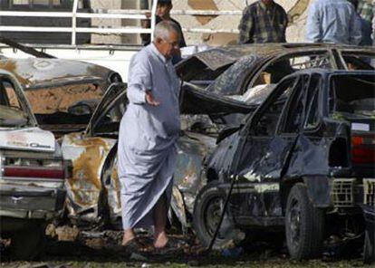 Un iraquí observa el estado en que quedó uno de los coches bomba que ayer explotaron en Bagdad.