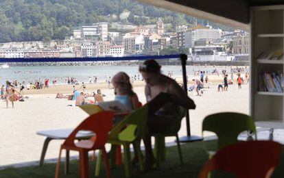 Una ni&ntilde;a y su madre en la biblioteca de La Concha, con la playa donostiarra al fondo.