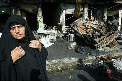 Una mujer pasa por delante de los restos de un coche bomba en la ciudad iraquí de Balad en 2005.