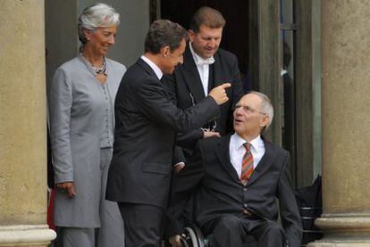 El presidente francés, Nicolás Sarkozy, saluda al ministro alemán de Economía, Wolfgang Schäuble, acompañado de su homóloga gala, Christine Lagarde.