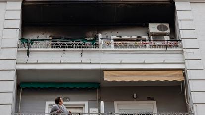 Una mujer observa desde su balcón el piso superior, en el número 51 de la calle Salamanca de València, donde esta madrugada se ha declarado un incendio en el que ha fallecido un hombre y dos mujeres han resultado heridas.