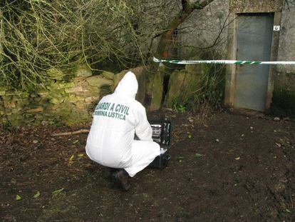 Un guardia civil toma muestras junto a la vivienda.