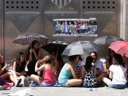 Un grupo de j&oacute;venes se protege del sol con paraguas a las puertas del estadio Vicente Calder&oacute;n.