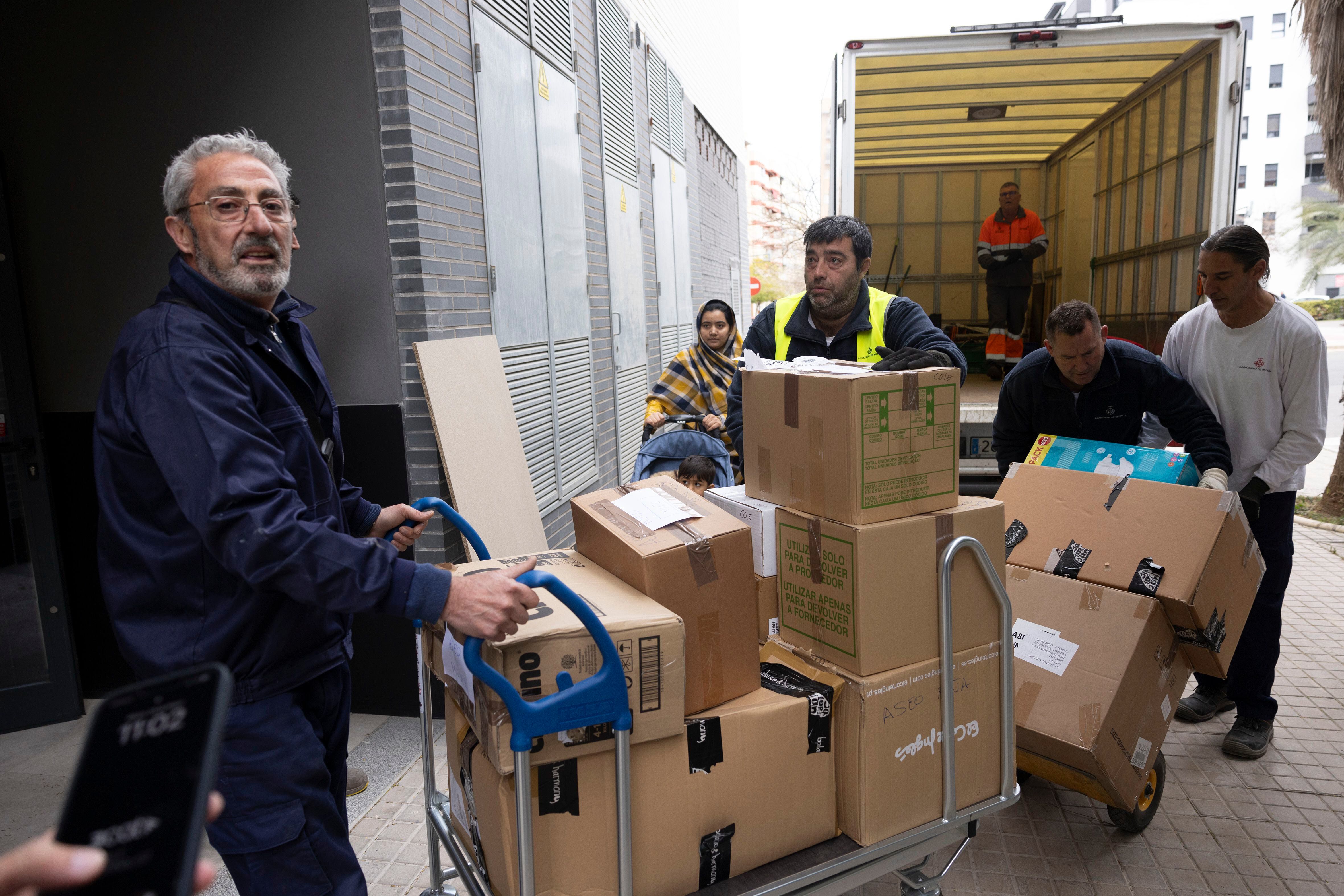 Operarios cargan cajas al interior del edificio donde se realojarán las familias afectadas por el incendio de Valencia, este lunes.