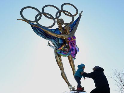 Un hombre juega con un niño junto a una escultura con los anillos olímpicos en el parque de Shougang, este martes en Pekín.