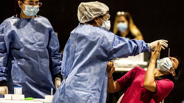 Un trabajador sanitario recoge una muestra de hisopo de una mujer para la prueba PCR del coronavirus.