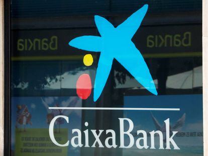 Logo de CaixaBank en una de sus oficinas con el reflejo del logo de Bankia, en Barcelona.