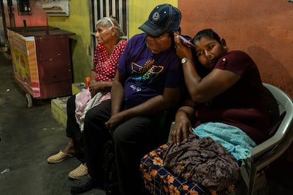 Tres personas esperan a un familiar detenido frente a la sede de El Penalito, en San Salvador. 
