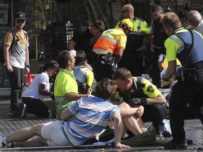 Agentes de policía, sanitarios y transeúntes atienden a los heridos en el atentado terrorista yihadista de La Rambla de Barcelona en 2017.