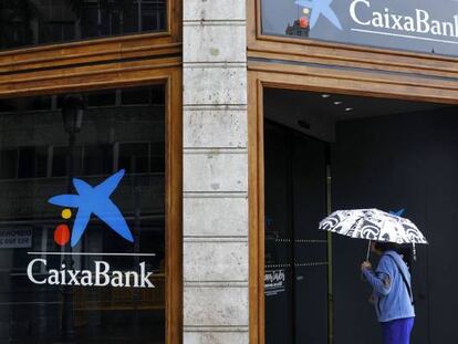 Una mujer observa el interir de la sede de Caixabank en la plaza del Ayuntamiento de Valencia. 