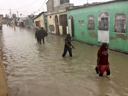 Un grup de persones caminen pels carrers inundats de Port-au-Prince, el Govern estima que van caure entre 38 i 63 centímetres d'aigua.