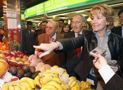 La presidenta indica a un frutero que quiere también unas cerezas ante la mirada del ex empresario.