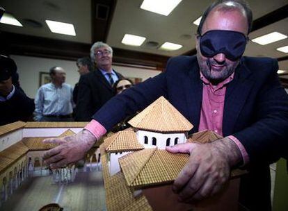 El teniente alcalde de Ourense, Alexandre Sánchez Vidal, con los ojos vendados, toca una de las maquetas de la exposición Ver y Tocar