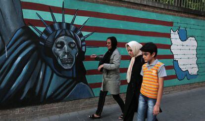 Una dona i els seus fills passen aquest dimarts per davant d'un grafiti pintat sobre el mur exterior de l'antiga ambaixada dels EUA a Teheran.