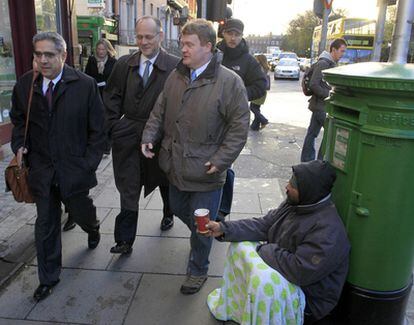 Ajai Chopra, representante del departamento del FMI en Europa, pasan junto a un mendigo en su camino a pie hasta la sede del Banco de Irlanda.