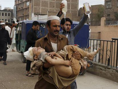 Un hombre lleva a un niño a un hospital después del seísmo en el que han muerto más de 200 personas en Pakistán y Afganistán.