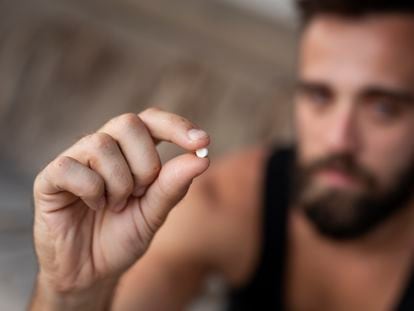 Un hombre sujeta una pastilla de éxtasis o MDMA.