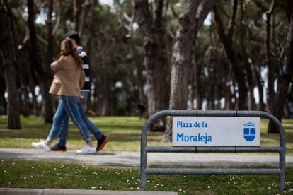 Dos personas caminan por la plaza de la Moraleja, una zona de comercios a la entrada de las urbanizaciones.
