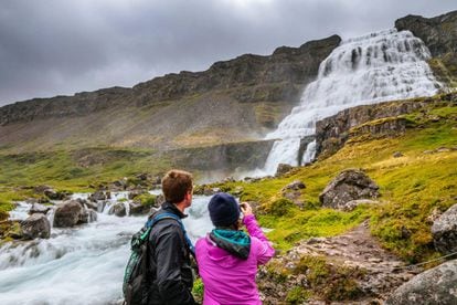 Una pareja fotografía la catarata de Dynjandi, la cascada más grande de la región de los Westfjords.