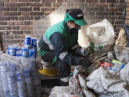 Una recicladora con mascarilla clasifica material reciclable en una nave de una asociación de recicladores de Bogotá.