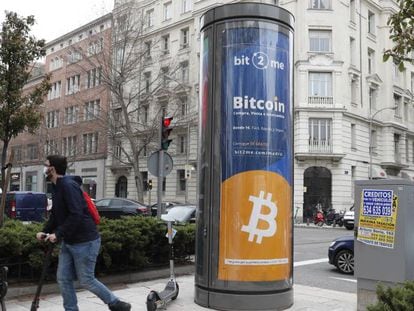 Un joven pasa junto a un panel de publicidad de bitcoin en Madrid.