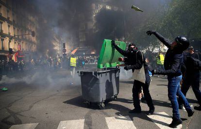 Un manifestante con casco lanza una botella de vidrio, durante los disturbios de este sábado en París.