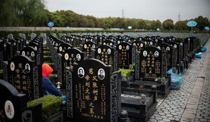 Una persona limpia una tumba, este lunes en un cementerio de Shang&aacute;i.