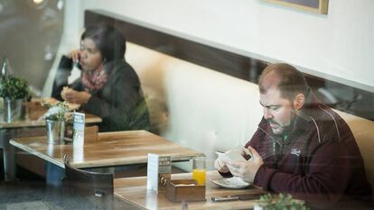 Dos personas desayunan enganchadas a sus dispositivos moviles