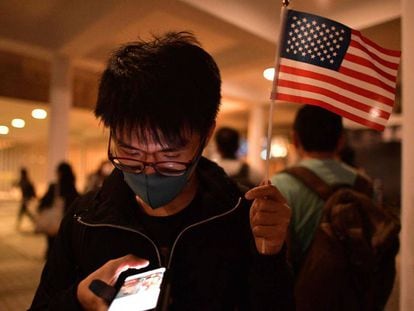 Un manifestante prodemocracia sostiene una bandera de Estados Unidos mientras revisa su teléfono, este jueves en Hong Kong.