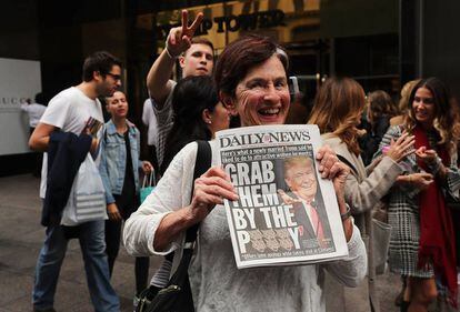 Una mujer muestra la portada de un diario sobre Trump. 
