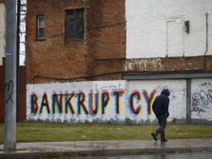 Un hombre camina delante de un grafiti en la una barriada de Detroit.