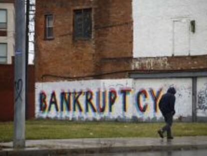 Un hombre camina delante de un grafiti en la una barriada de Detroit.