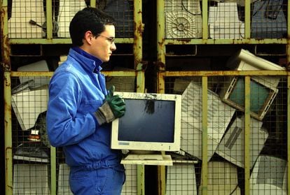 Un operario traslada un viejo monitor de ordenador en la empresa vasca de reciclaje de chatarra tecnol&oacute;gica Indumetal Recycling.