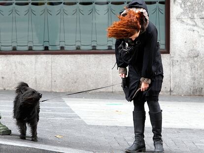 Una mujer y su perro soportando el temporal de viento en los alrededores de Plaza de España, de Madrid