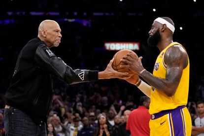Kareem Abdul-Jabbar entrega un balón a LeBron James después de que el actual '6' de los Lakers rompiera el récord de puntos del exjugador del mismo equipo.  Al romperse el récord se hizo una pausa en el partido, con diez segundos en el reloj del tercer cuarto, para reconocer a James con una breve ceremonia.