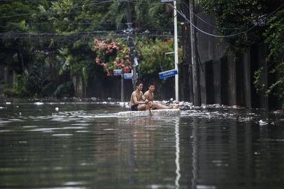 Dos personas reman sobre una balsa improvisada a través de una calle inundada en Quezon City, al este de Manila (Filipinas).